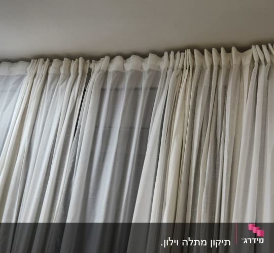 וילונות לבנים תלויים על מוט בחדר מואר